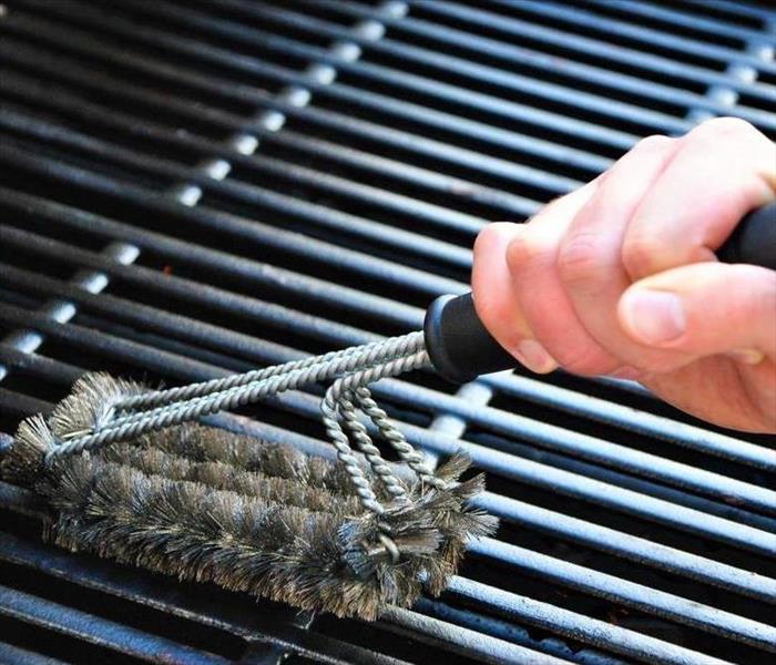 Person cleaning a grill.